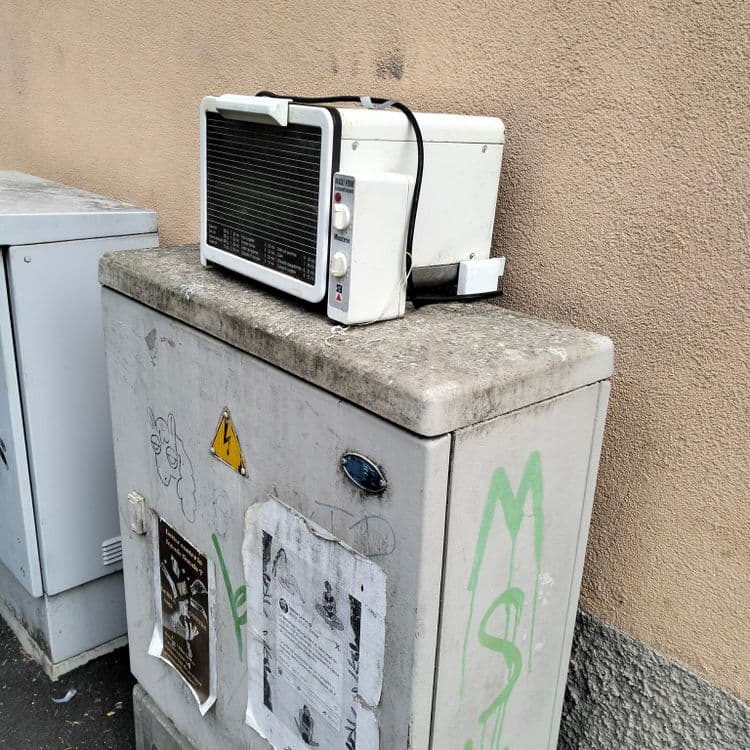 Mini four abandonné sur une armoire électrique située au bord d'un immeuble 