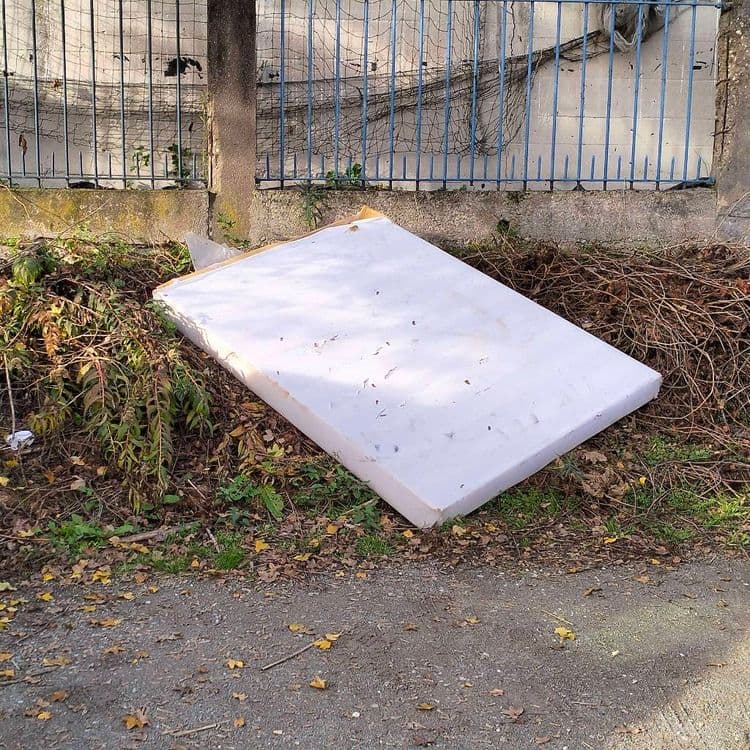 Matelas abandonné sur un parking de jardins ouvriers 