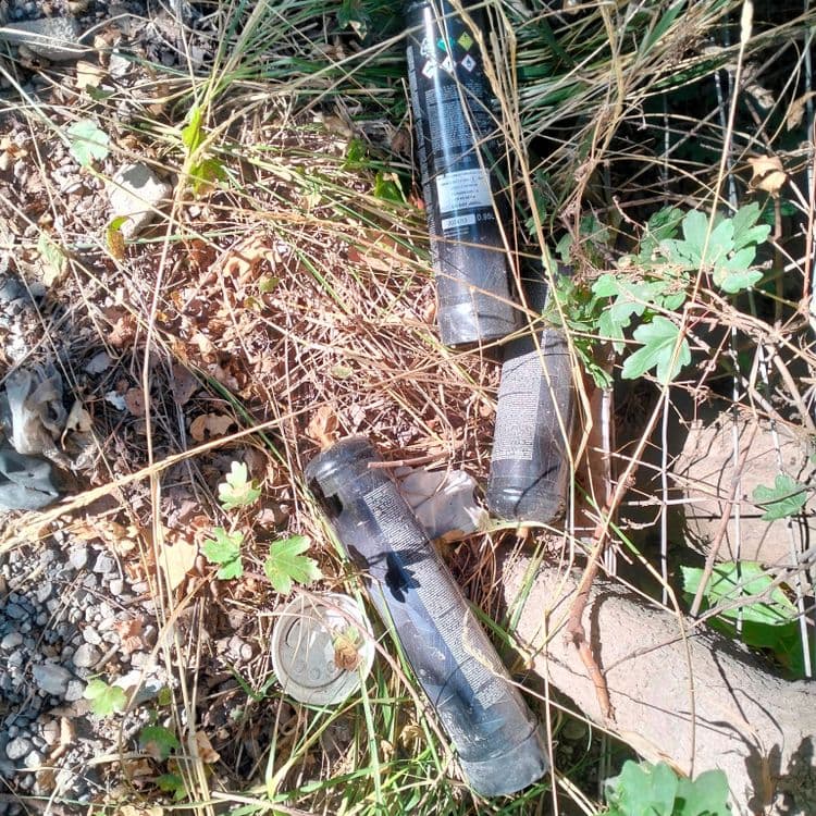 Déchets divers et bouteilles de protoxyde d'azote abandonnés sur un chemin en bordure d'autoroute 