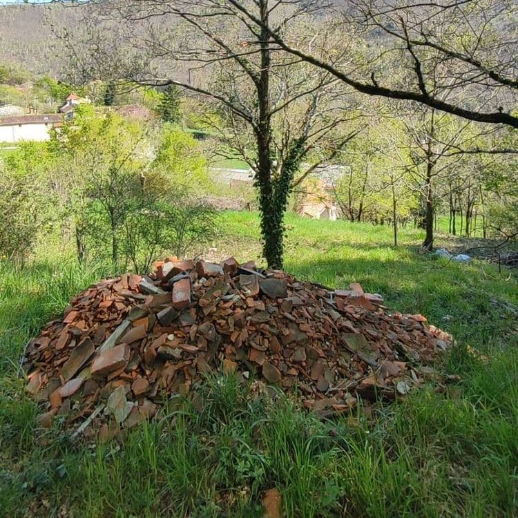 Voici l'analyse des déchets présents sur le site, destinée à la commune :

On observe un dépôt sauvage constitué principalement de débris de construction en terre cuite. Il s'agit en grande partie de fragments de tuiles et de briques concassées.

Estimation des quantités et du poids :

*   **Débris de tuiles** : Quantité estimée : environ 300 à 400 fragments. Poids total estimé : 150 à 250 kg.
*   **Débris de briques** : Quantité estimée : environ 100 à 200 fragments. Poids total estimé : 100 à 200 kg.

Le poids total estimé de l'ensemble des déchets de construction s'élève donc à environ 250 à 450 kg.
