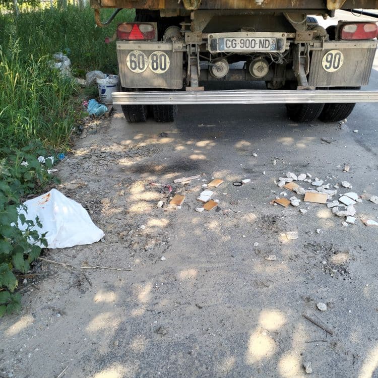 Palettes, pots de peinture et déchets divers abandonnés au bord d'une route 