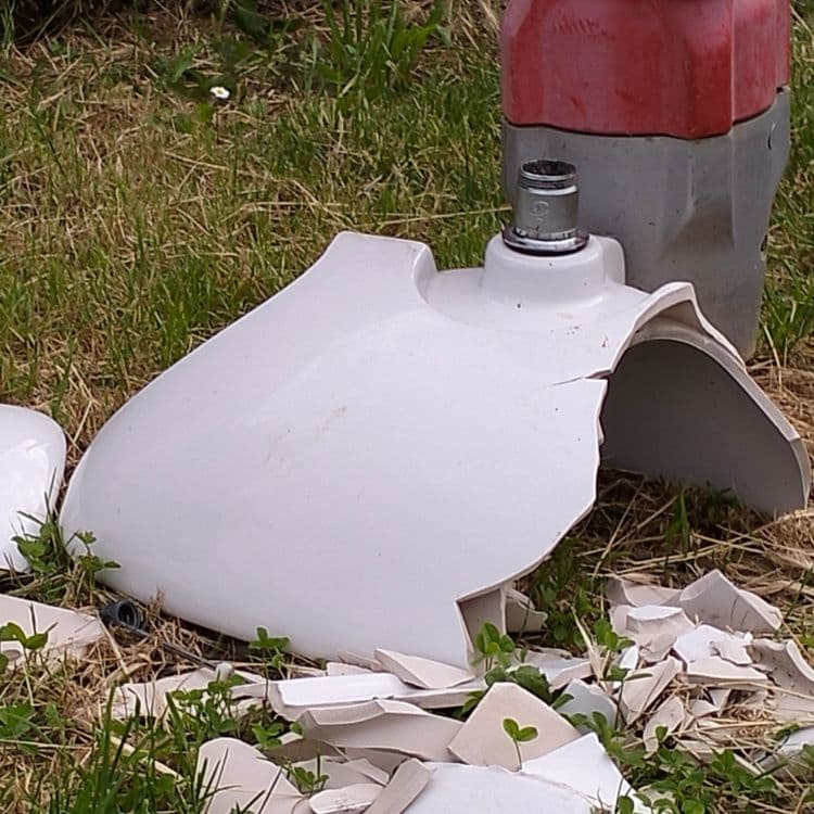 Lavabo cassé et pièce plastique à côté d'une borne incendie, sur le trottoir 
