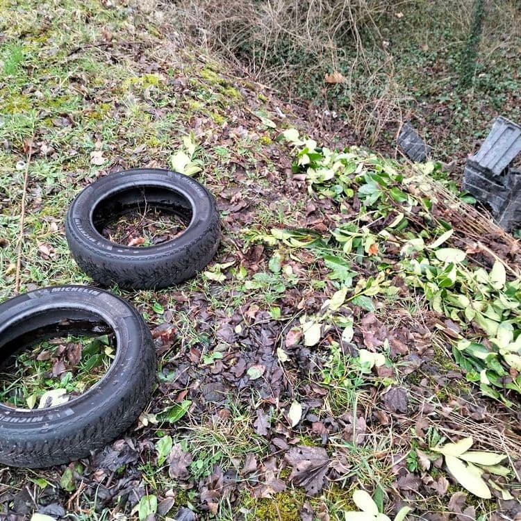 Pneus usagés et pièces auto en plastique abandonnés au bord de la route 