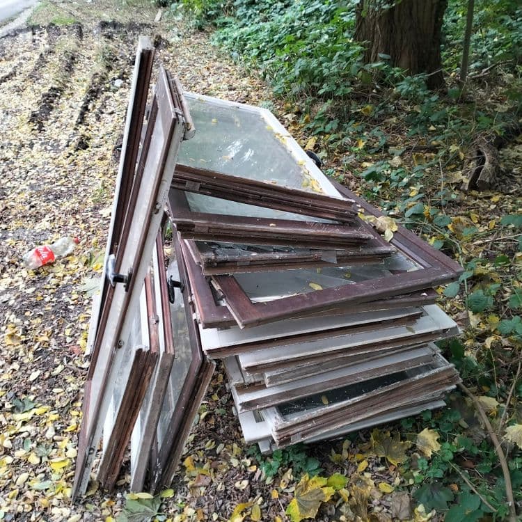 Un lot de vieilles fenêtres en bois au bord de la route et d'un bois 