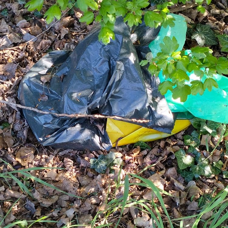 Sac poubelle abandonné au bord d'une piste cyclable 
