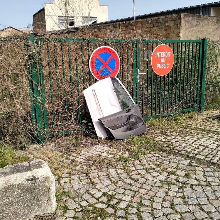 Portière de voiture abandonnée au bord de la route contre un portail