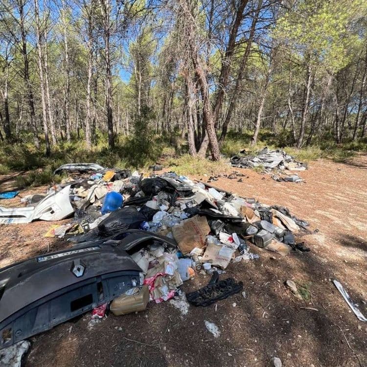 L'aire présente un dépôt sauvage composé de plusieurs types de déchets.
* **Déchets automobiles (plastiques et composites) :** On dénombre environ 5 à 7 pièces majeures, telles que des pare-chocs et des éléments de carrosserie, ainsi que plusieurs fragments plus petits. Le poids estimé pour cette catégorie est d'environ 60 kilogrammes.
* **Sacs poubelles noirs (déchets ménagers et divers) :** Une quantité importante de sacs est présente, avec une estimation d'au moins 15 à 20 sacs, dont certains sont éventrés, révélant un mélange de déchets. Le poids total pour cette catégorie est estimé à environ 140 kilogrammes.
* **Cartons et emballages :** Environ 5 à 8 cartons de différentes tailles sont visibles, certains intacts, d'autres déchirés. Le poids estimé est d'environ 8 kilogrammes.
* **Bidons et bouteilles en plastique :** On observe une dizaine à une quinzaine de bidons et bouteilles, incluant des contenants d'huile et d'autres liquides. Le poids estimé pour ces éléments est d'environ 8 kilogrammes.
* **Textiles et chiffons :** Quelques pièces de tissus et chiffons sont éparses dans le tas. Le poids estimé est d'environ 3 kilogrammes.
* **Ferraille et petits objets métalliques :** Quelques éléments métalliques sont présents. Le poids estimé est d'environ 5 kilogrammes.