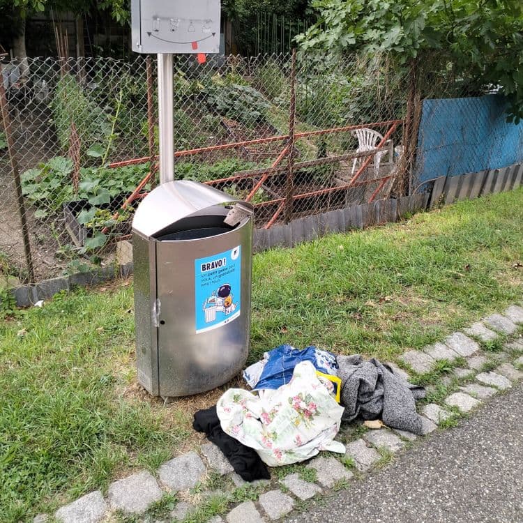 Vêtements abandonnés à côté d'une poubelle de rue