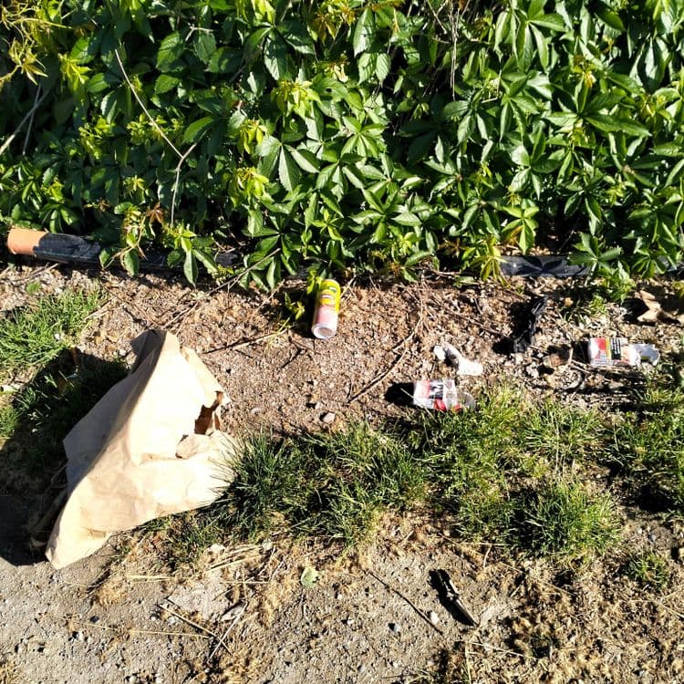 Vêtements et déchets divers abandonnés sur un parking public